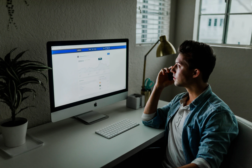 Man on phone while sitting in front of computer